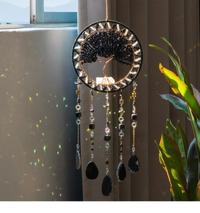 Detail of tree of life suncatcher with black stones and crystals casting rainbow light