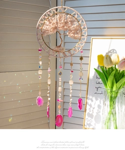 Detail of Tree of Life suncatcher with pink crystals and agate slices hanging by a window