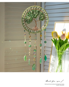 Detail of life tree suncatcher with green crystal stones hanging by a window