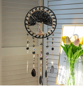 Detail of life tree wall hanging with black stones and agate slices by a sunny window