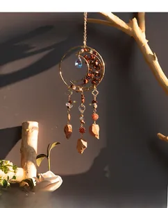 Detail of moon-shaped dreamcatcher with red natural agate stones and blue crystal drop
