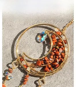 Detailed close-up of golden tree of life pendant with red agate stones and crystal drop