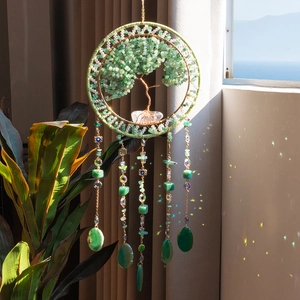 Tree of Life suncatcher with green crystals and evil eye hanging in a sunny room