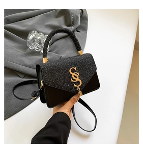 Détail du rabat pailleté et du logo S doré sur le sac bandoulière en cuir noir