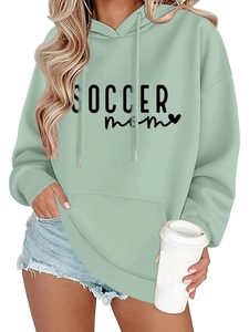 Detail of sage green hoodie featuring SOCCER MOM print and kangaroo pocket texture