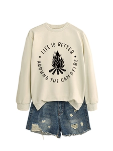 Flat lay of cream sweatshirt with campfire print and distressed blue denim shorts