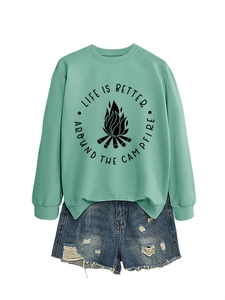 Flat lay of mint green sweatshirt with campfire print and distressed denim shorts