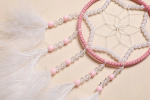 Dettaglio dell'acchiappasogni rosa per auto con piume bianche e trama di perle octo