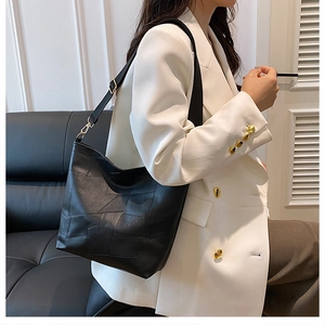 Detail of black geometric stitched tote bag with adjustable strap on a white suit model