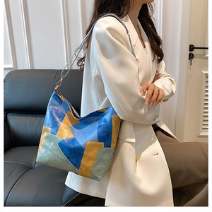 Artistic patchwork tote bag with multicolored faux leather panels in a stylish home setting
