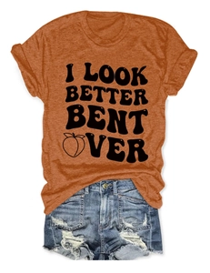 Flat lay of an orange crewneck T-shirt with vintage text and distressed denim shorts