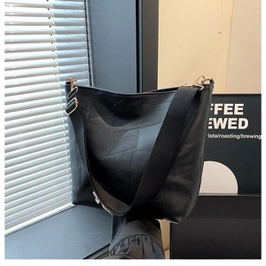 Detail of black patchwork leather shoulder bag with adjustable strap and metal hardware