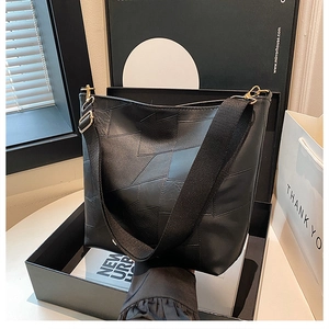 Detail of black geometric patchwork bucket bag with wide strap and gold hardware
