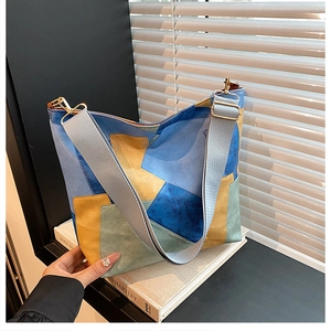 Detail of color-block bucket bag with matte suede texture and wide gray strap