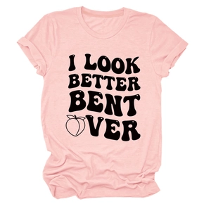 Flat lay of pink cotton T-shirt with I LOOK BETTER BENT OVER text and peach graphic