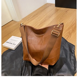 Detail of brown leather tote featuring geometric texture and adjustable wide strap