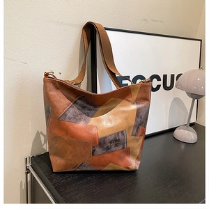 Detail of multi-tone patchwork leather tote bag on an industrial side cabinet
