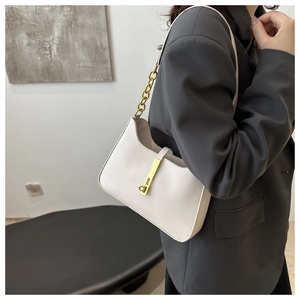 Detail of minimalist cream leather crescent bag with golden buckle and chain strap on model
