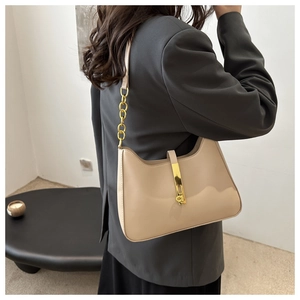 Detail of beige hobo bag with gold piston clasp and chain strap on stylish model