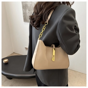 Detail of minimalist beige leather crescent bag with gold chain strap and metal lock