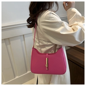 Detail of rose red leather hobo bag featuring vintage gold piston buckle closure