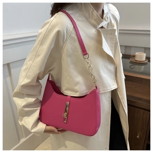 Detail of rose red crescent bag with gold piston closure and leather chain strap