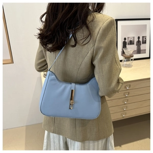 Close-up of light blue leather crescent bag featuring a golden piston lock on a model