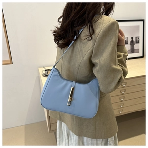 Detail of light blue leather crescent bag with golden metal buckle clasp on model