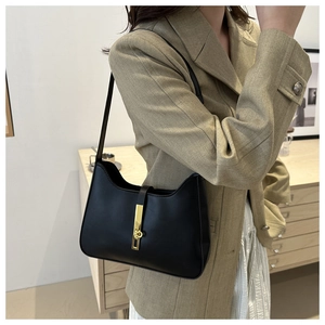 Detail of a black leather hobo bag with a distinctive gold metal clasp on a model