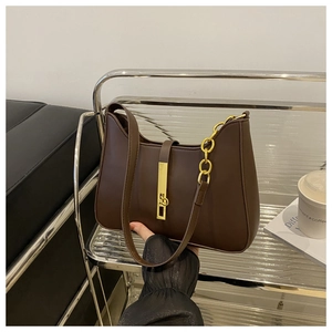 Detail of dark brown leather crescent bag with golden chain and metal clasp