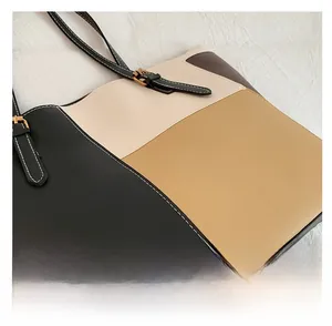 Detail of color block tote bag featuring contrast stitching and golden metal buckle