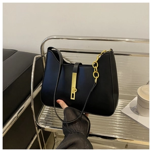 Detail of black semi-circular hobo bag featuring gold chain and vertical metal lock