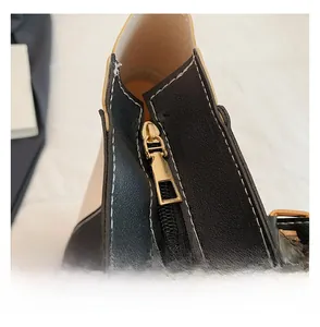 Close-up of contrast leather tote with white stitching and smooth gold metal zipper detail