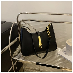 Detail of black leather hobo bag with gold buckle on a modern minimalist display stand