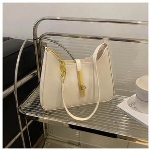 Chic cream white crescent bag with gold clasp shown on a glass table in a stylish setting
