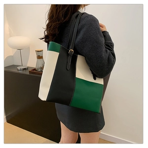 Detail view of large color-block tote bag in green and white worn by a model
