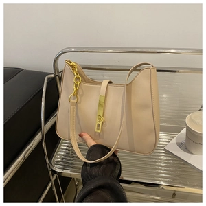 Detail of cream white crescent bag with gold chain and metal buckle in lifestyle setting