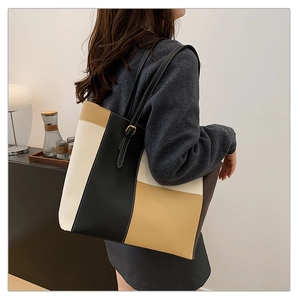 Detail of color-block tote bag with contrast stitching and golden metallic buckle