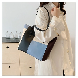 Detail of color-block tote bag showing geometric patchwork and adjustable shoulder strap