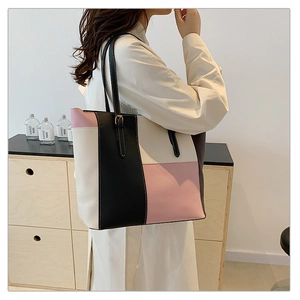 Close-up of tricolor tote bag in cream, black, and pink PU leather with shoulder straps