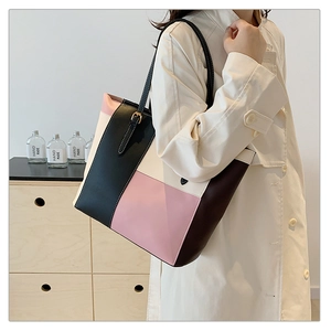 Detail of color-block tote bag with pink and cream PU panels and gold buckle strap
