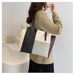 Detailed view of color-block tote bag featuring geometric stitching and metal strap buckle