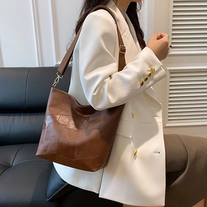 Brown geometric patchwork underarm bag shown on model with retro minimalist design