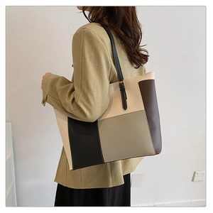 Contrast color patchwork tote bag shown on shoulder of a model in green blazer