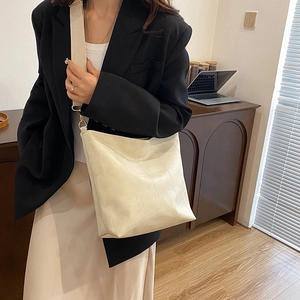 Minimalist beige bucket bag with geometric texture and wide shoulder strap