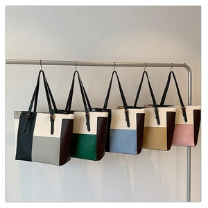 Close-up of color-block tote bags showing matte leather texture and adjustable gold buckles