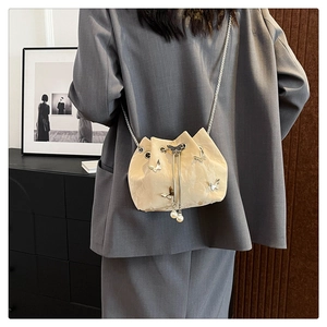 Detail of cream white bucket bag with silver butterfly charms and pearl drawstrings