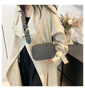Detail of grey crossbody bag featuring white M-letter print and adjustable wide strap