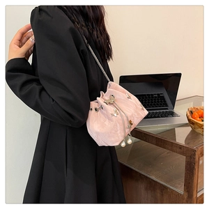 Detail of pink bucket bag with pleated texture, metal butterfly, and pearl drawstrings