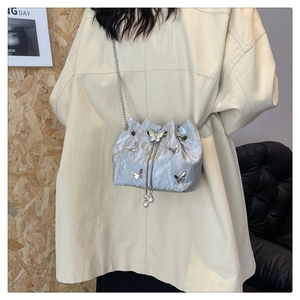 Detail of silver bucket bag with butterfly accents, pearl drawstrings and chain strap